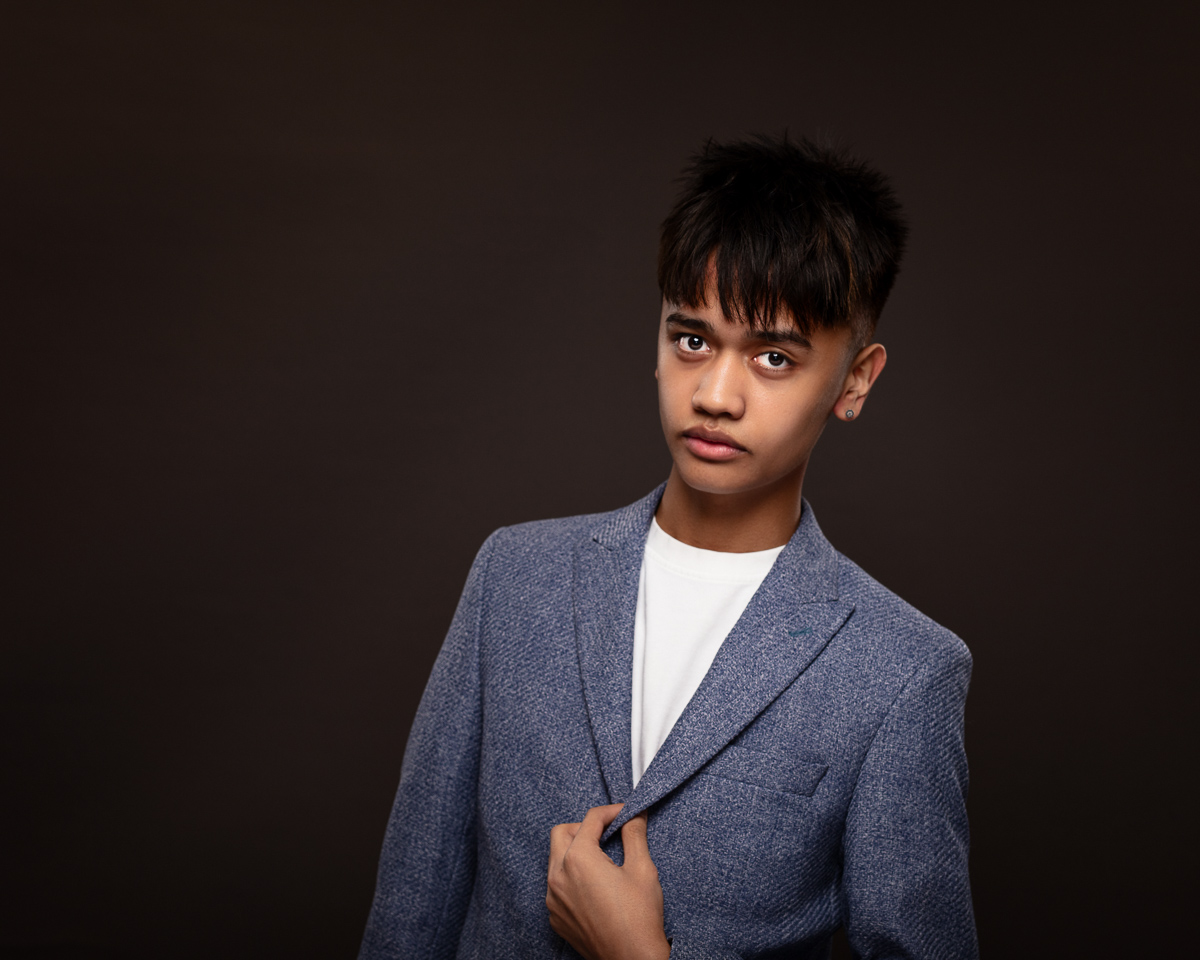 Young person in blue blazer, dark background