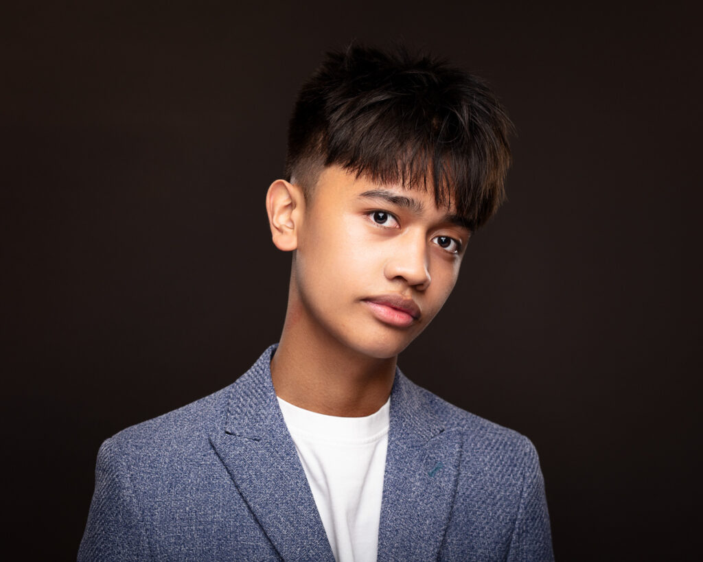 Young person in blue blazer, dark background