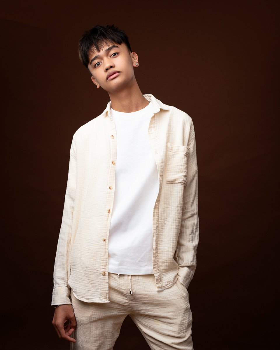 Person in cream outfit against brown background