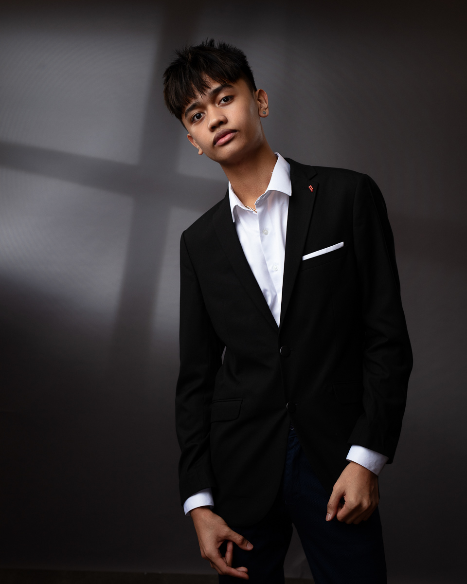 Person in black suit, white shirt, serious expression