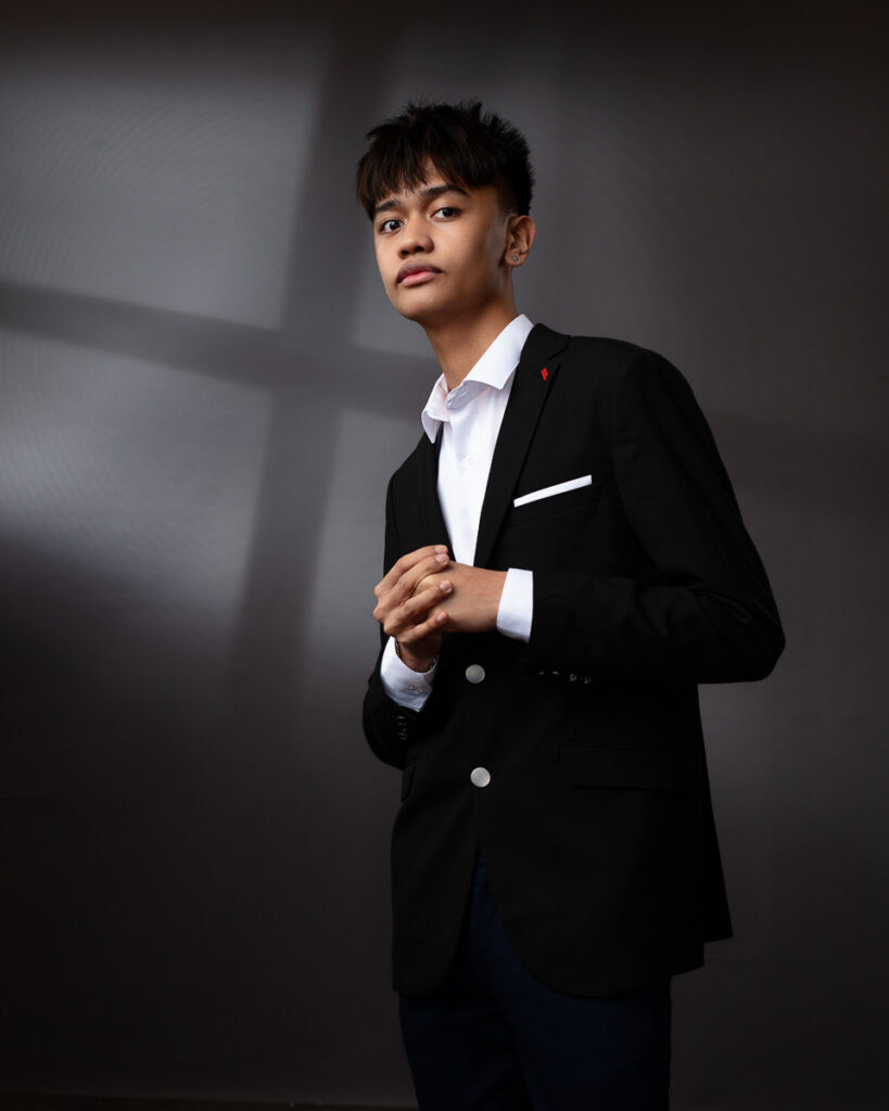 Person in a black suit posing confidently.