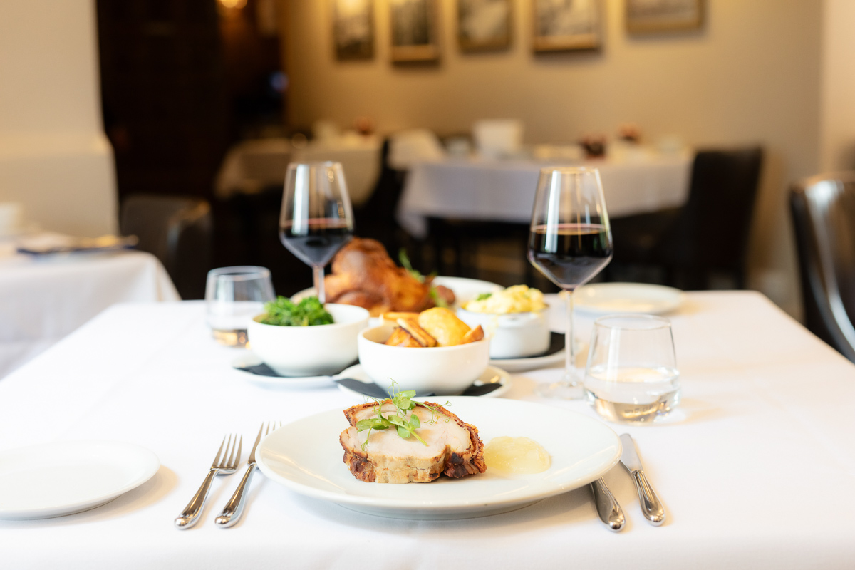 Dining table set with a roast dinner and wine in the restaurant at Seckford Hall