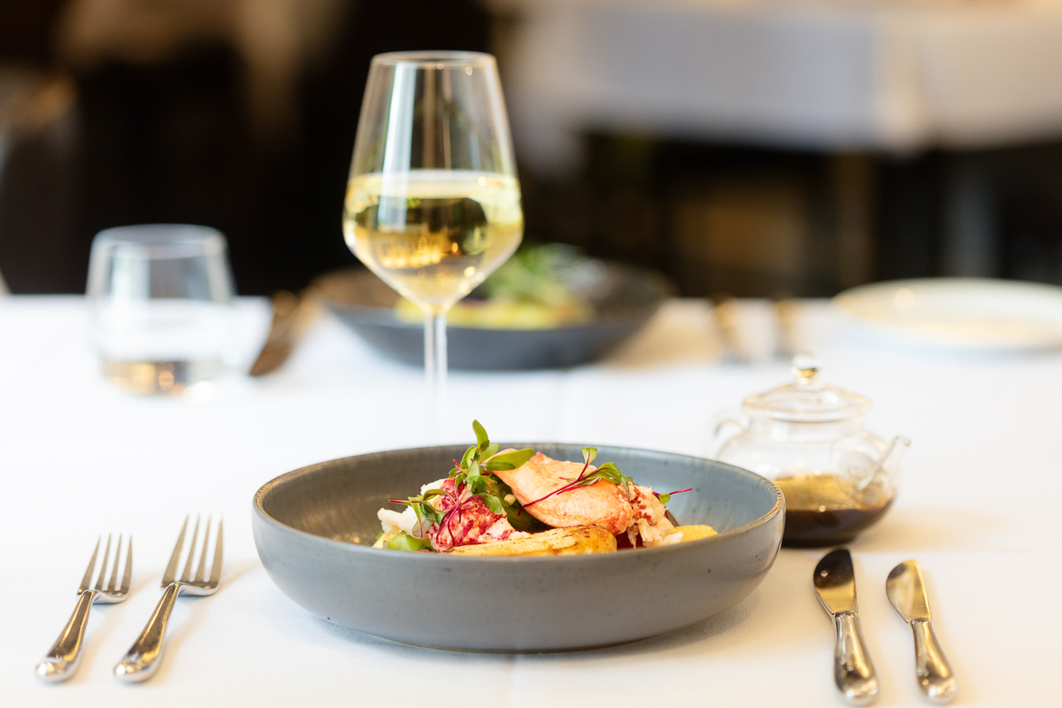 Commercial food photograph of a plated salad and a glass of white wine at Seckford Hall
