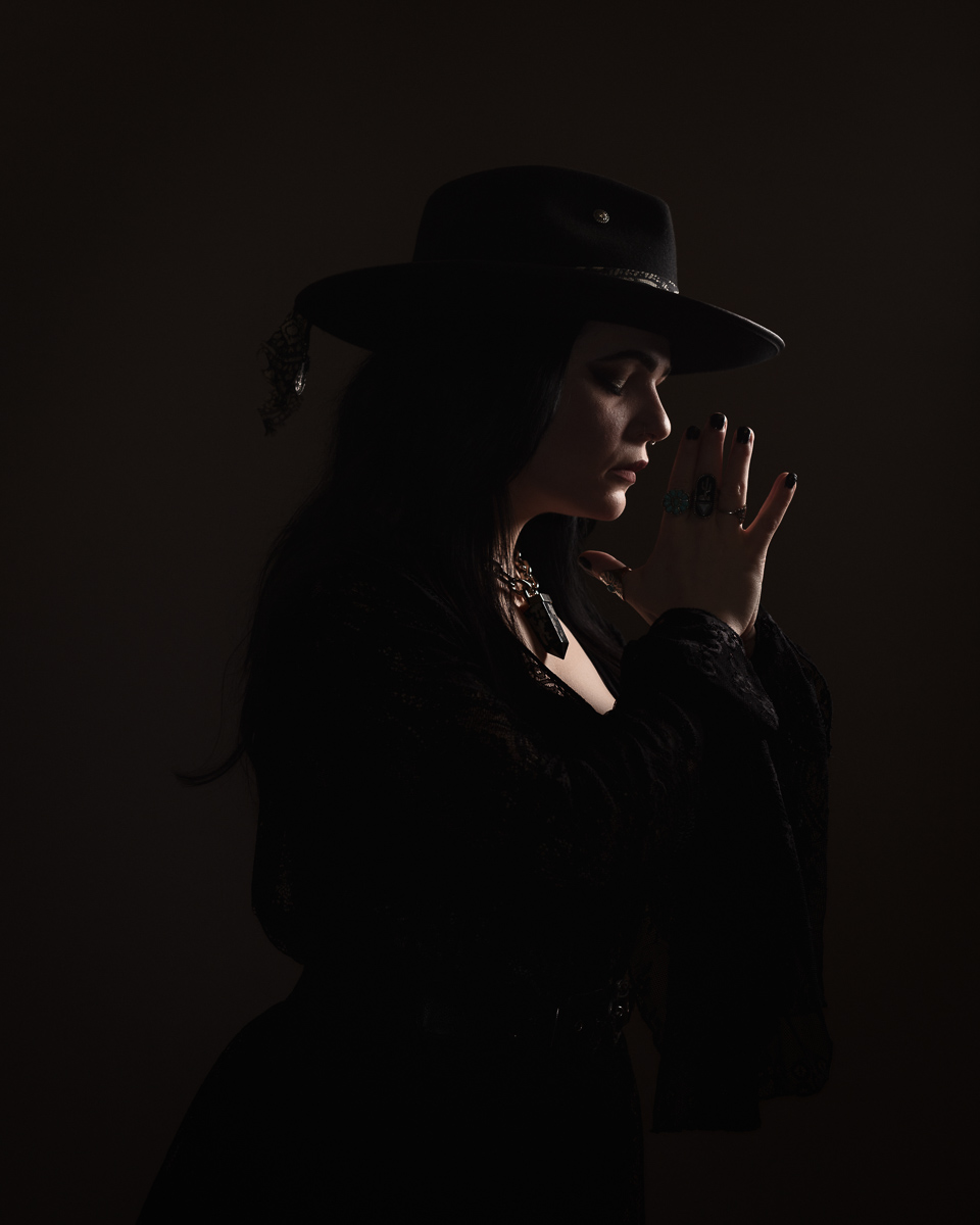 Silhouette of woman in hat, prayer pose.