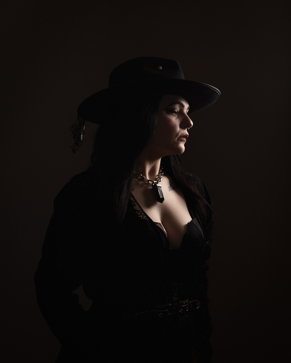 Woman in dark attire and hat, side view.
