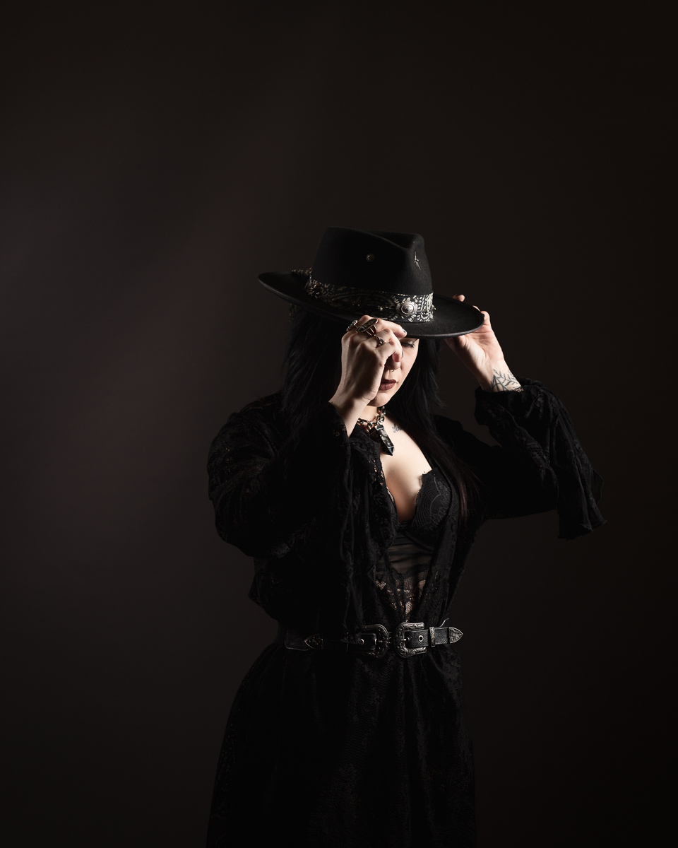 Woman in black outfit adjusting stylish hat