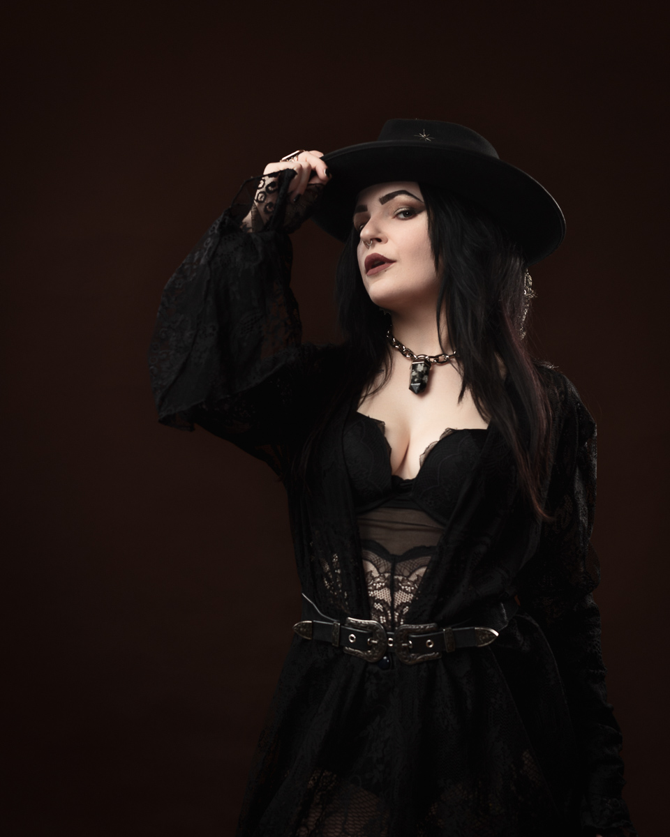 Woman in gothic outfit wearing hat.