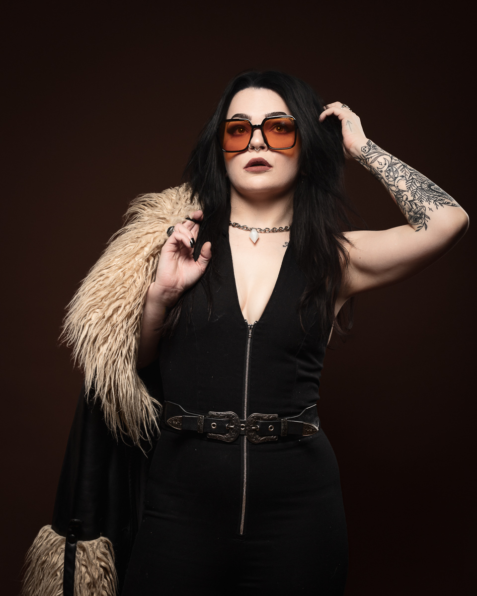 Woman in sunglasses with tattoos and fur coat.