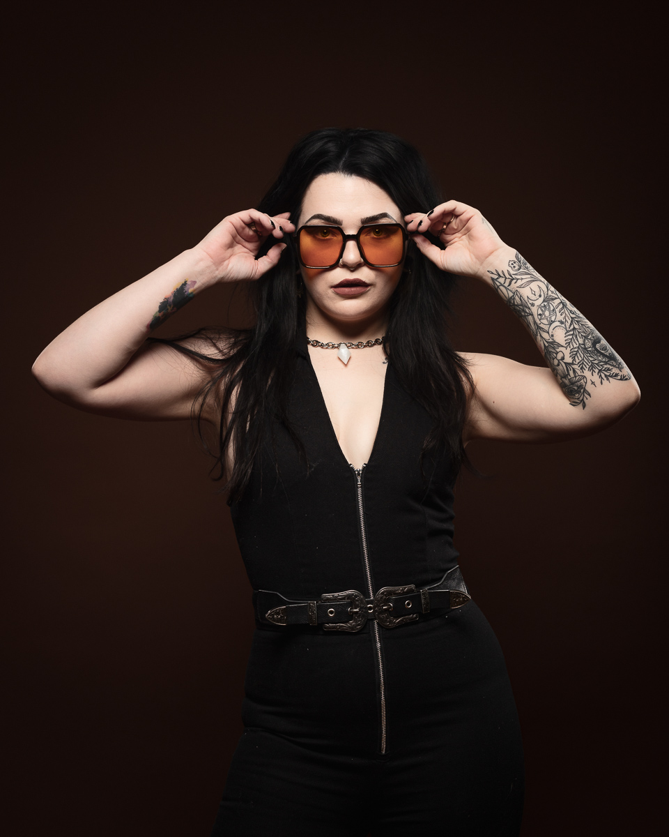 Woman with tattoos wearing sunglasses and black outfit