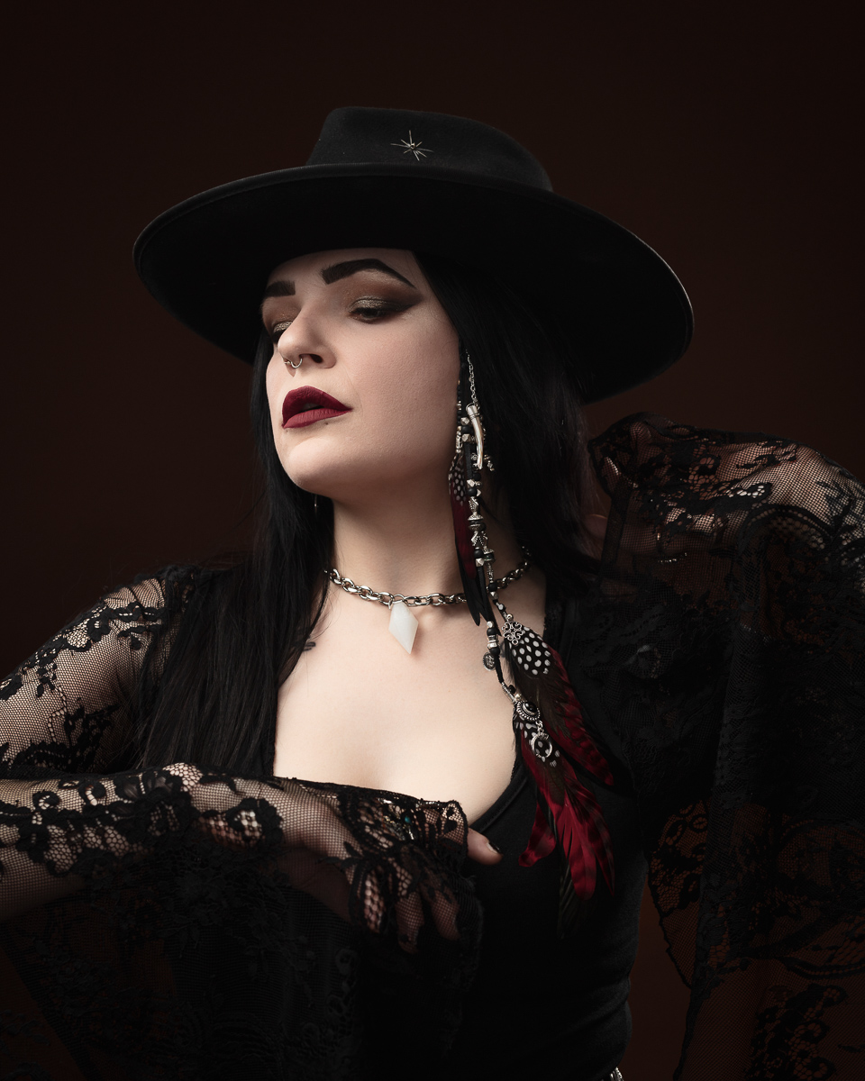 Elegant woman in hat with dark lace attire.