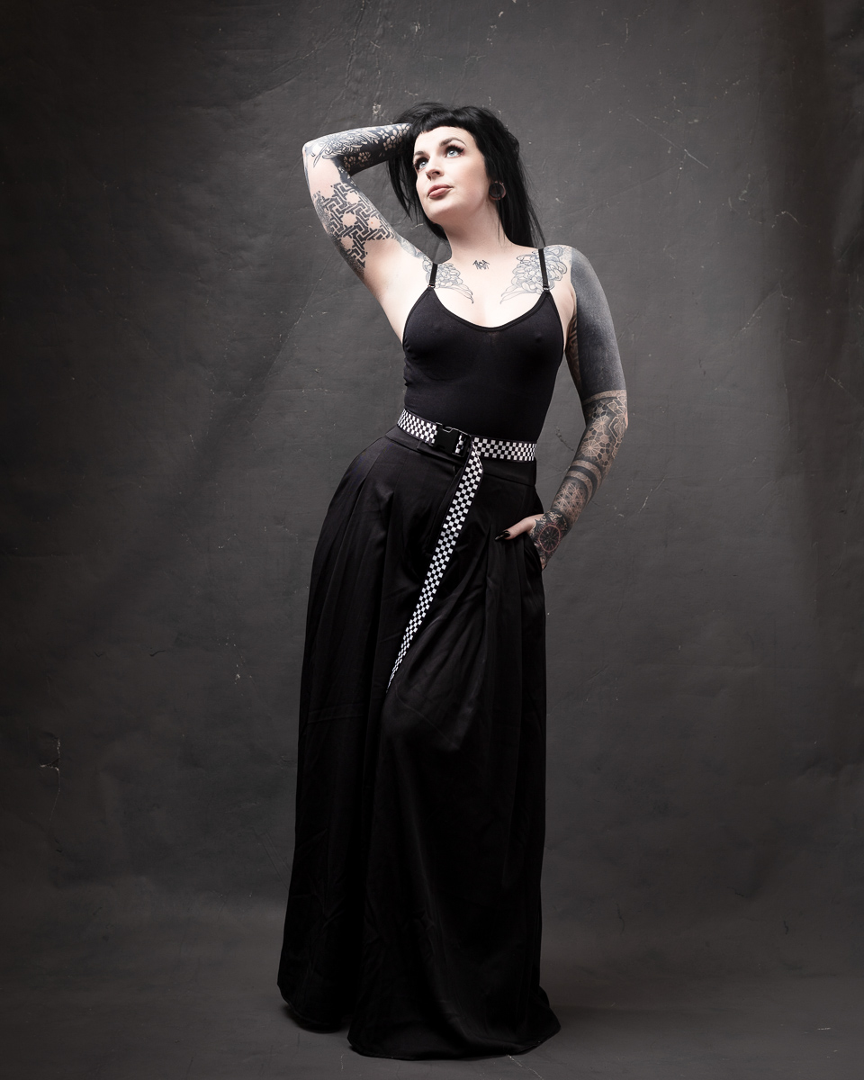 Tattooed person posing in black outfit.
