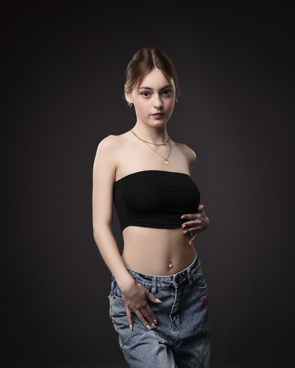 Woman in black top and jeans posing confidently.
