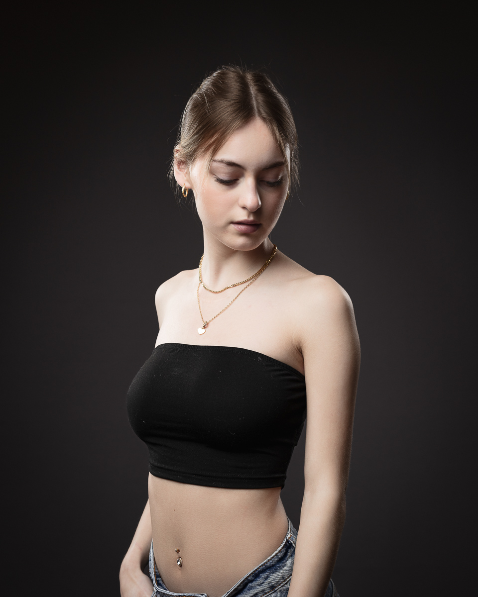 Young woman in black strapless top, studio portrait.