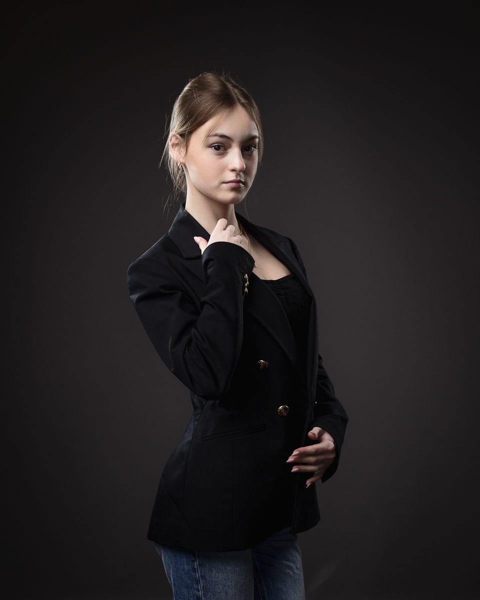 Woman posing in black blazer and jeans.