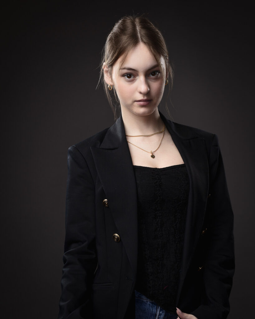 Person wearing black blazer, dark background.