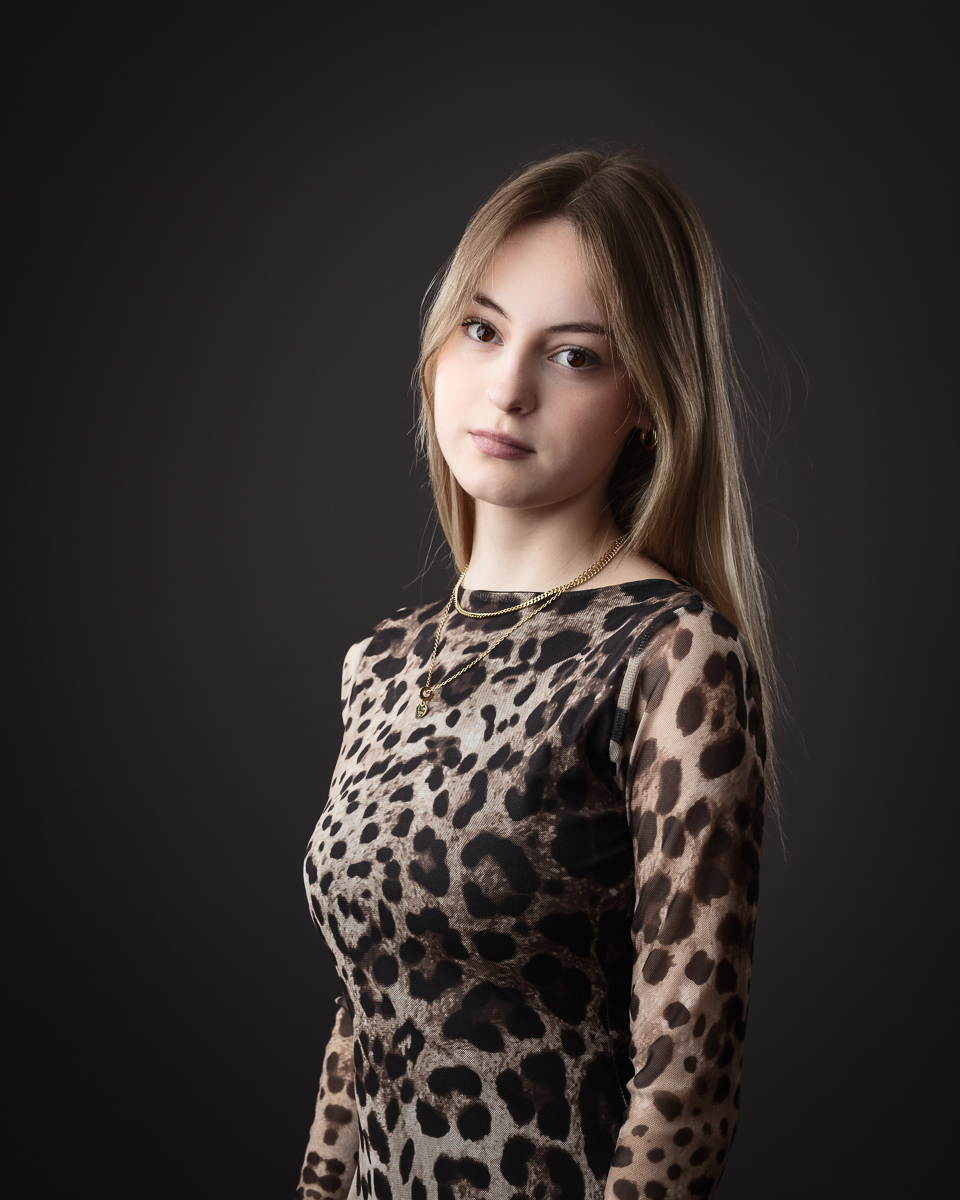 Blonde woman in leopard-print dress, black background.