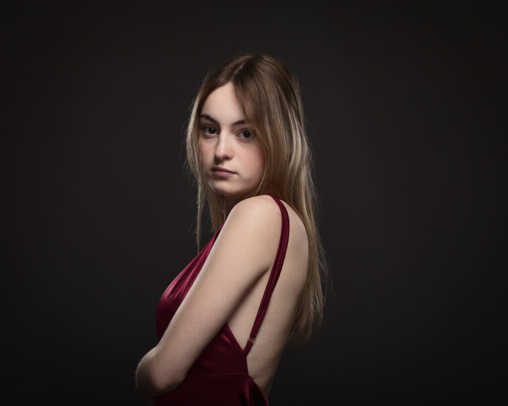 Woman in elegant red dress on dark background.