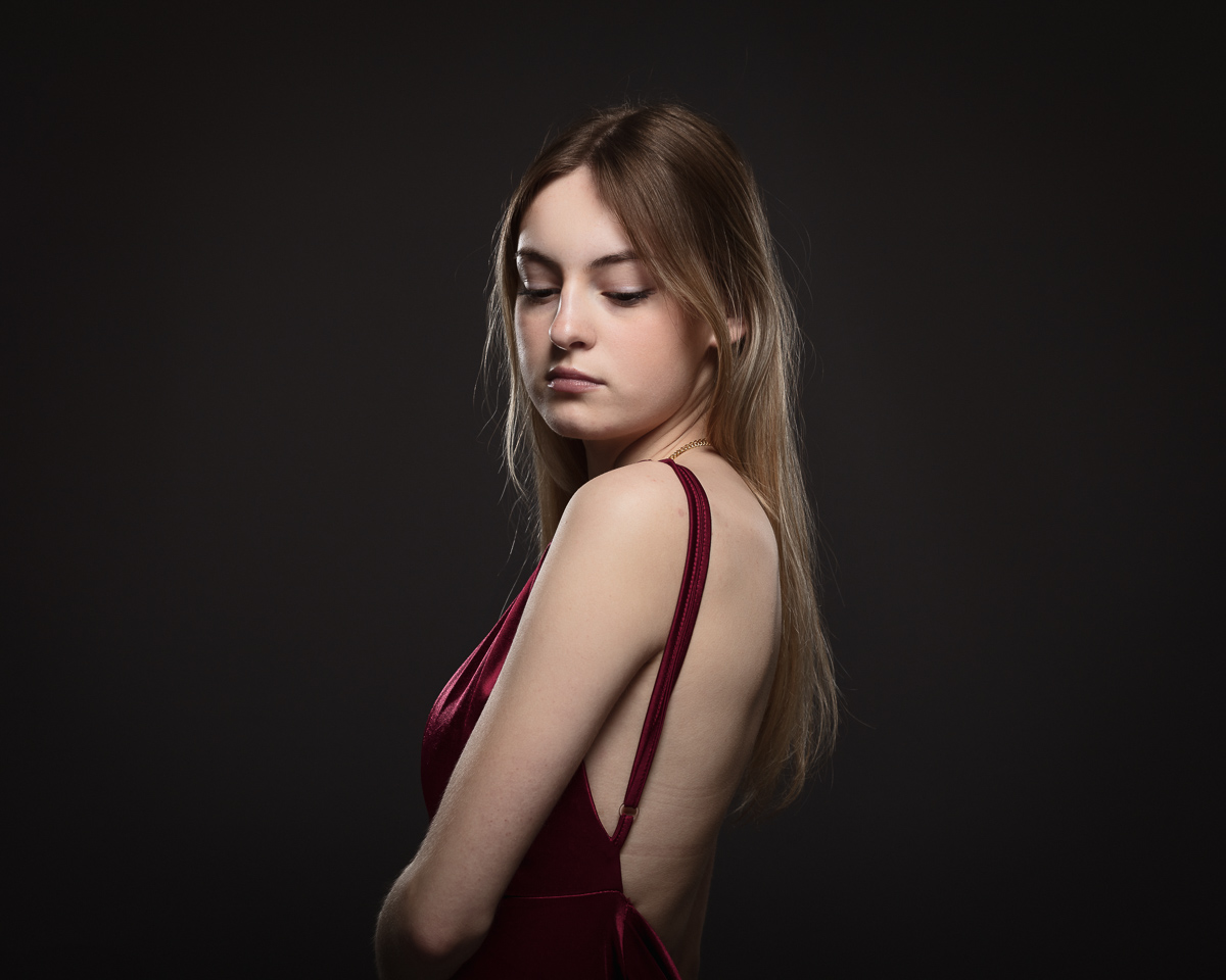 Woman in red dress with dark background.