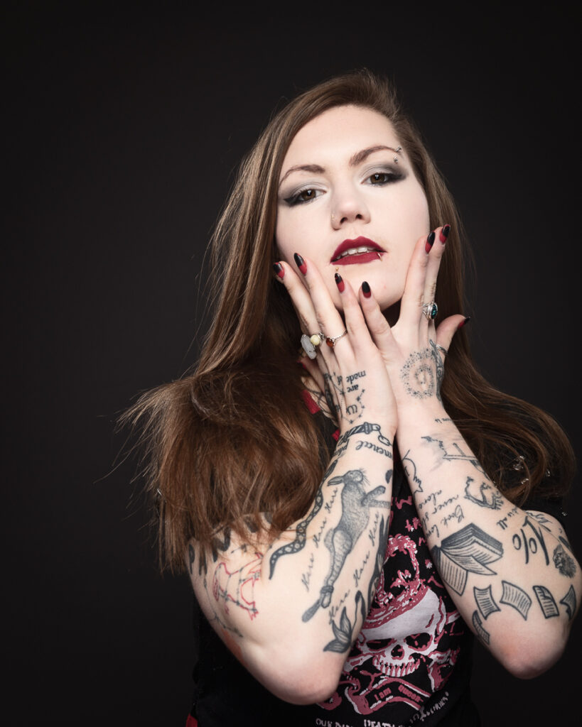Tattooed woman with dramatic makeup and black nails.