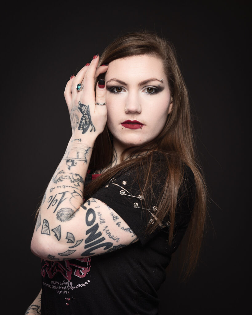 Woman with tattoos posing against dark background.