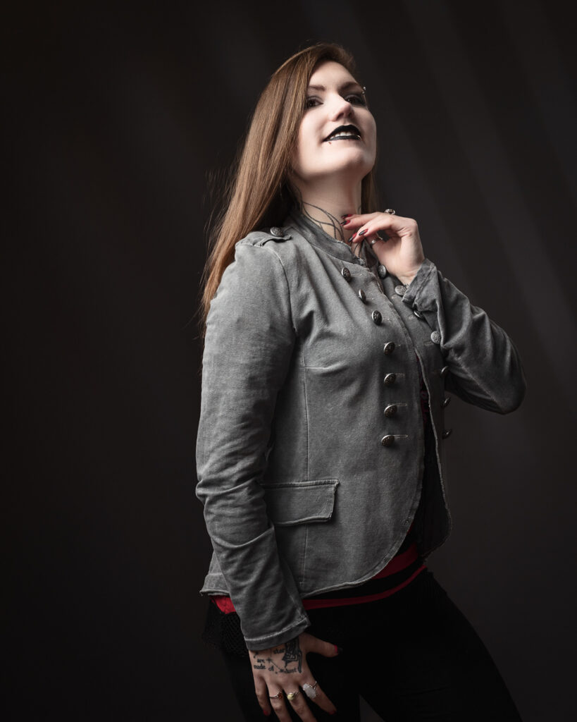 Smiling person in grey jacket with tattoos.