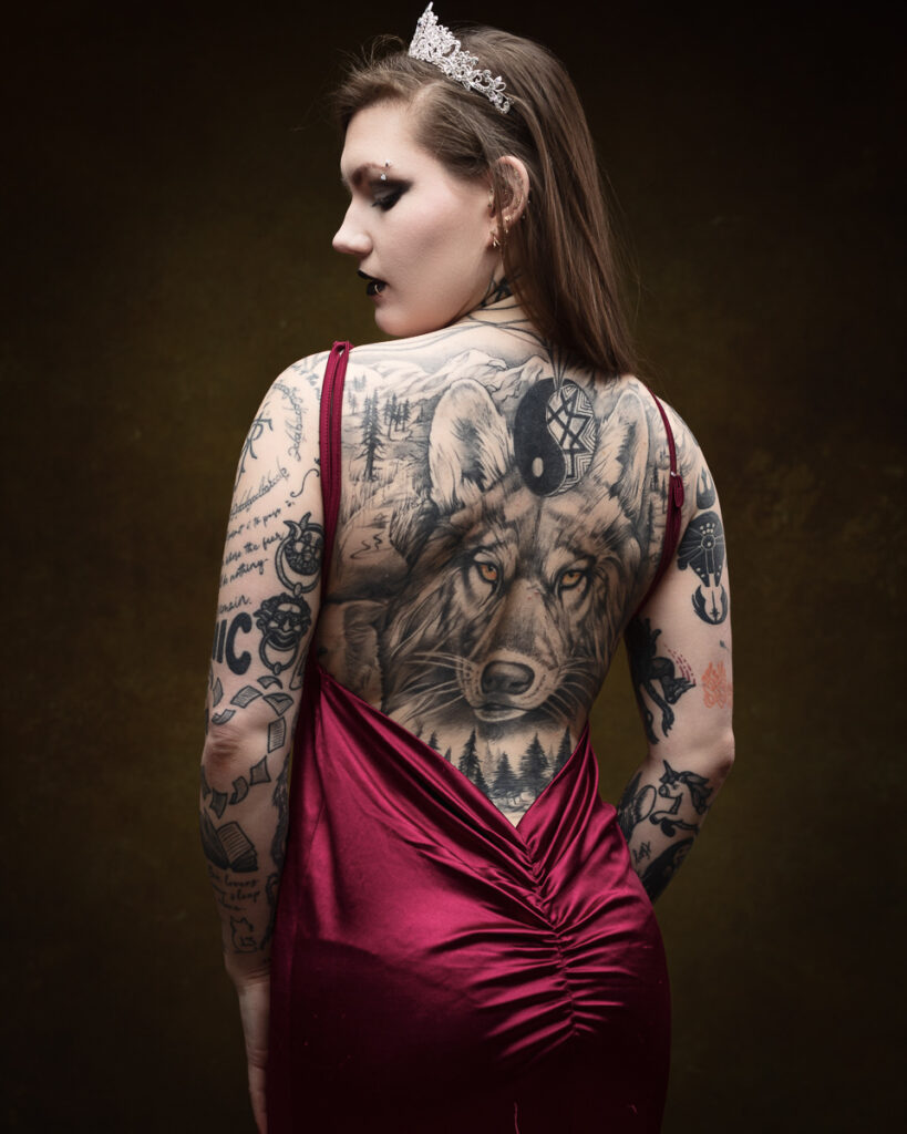 Woman with wolf tattoo on her back, wearing tiara.
