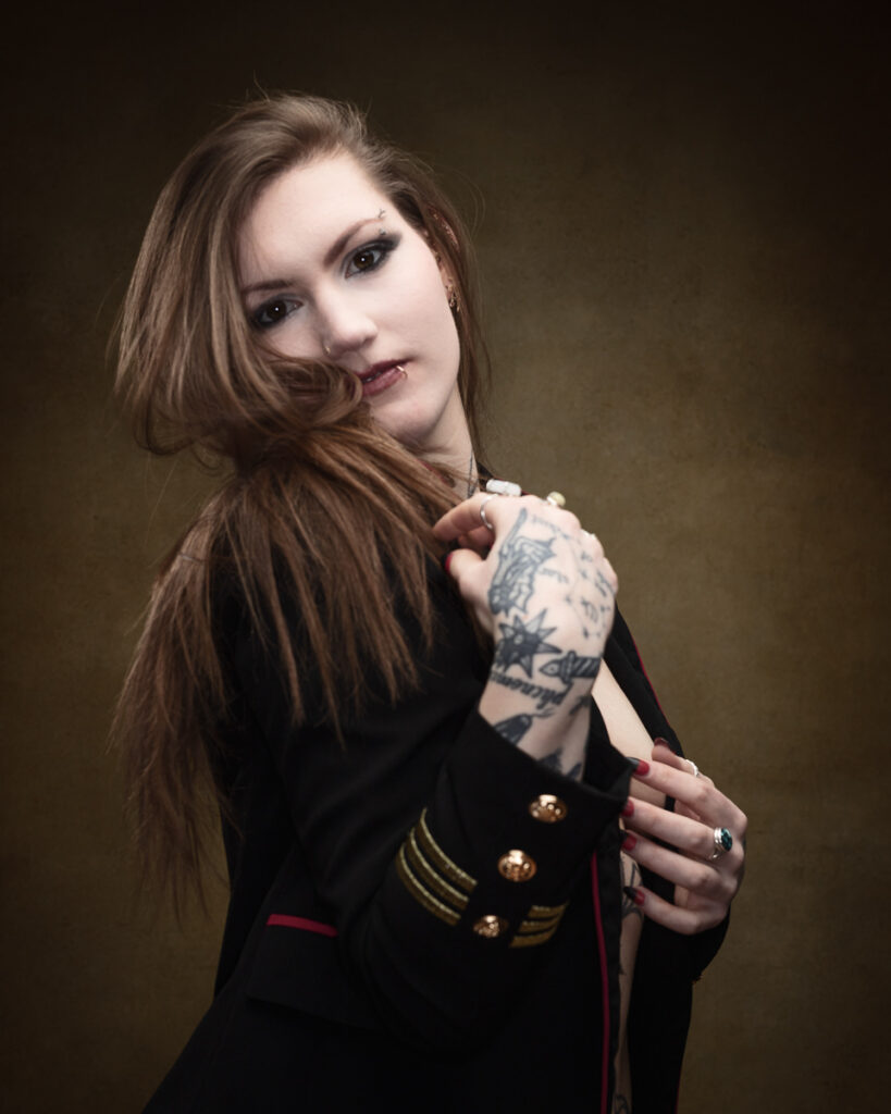 Person with tattoos posing against dark background