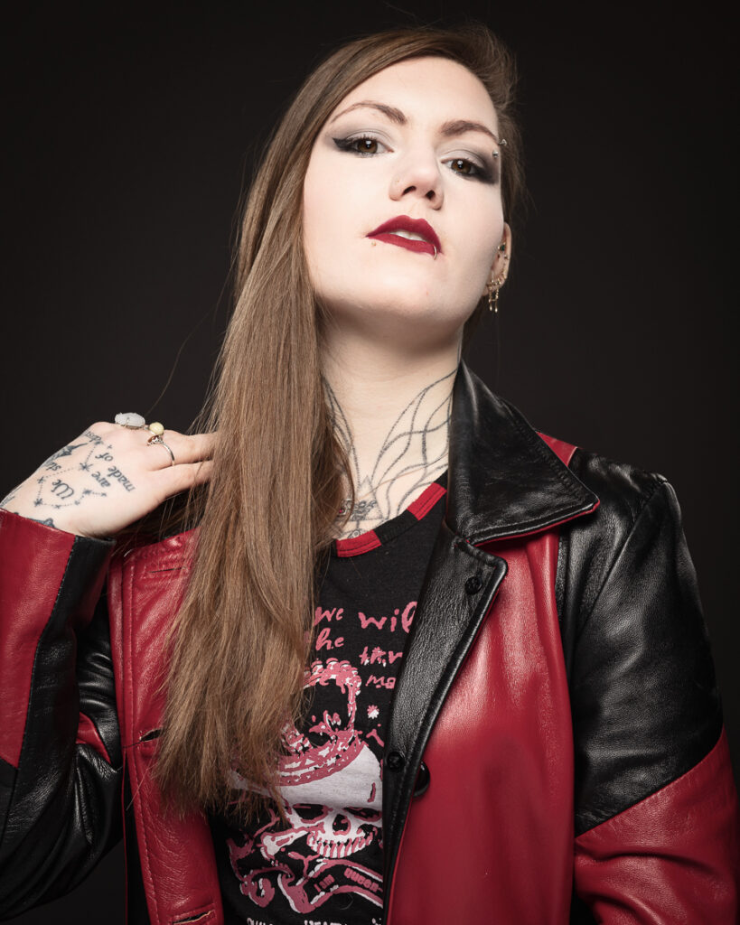 Person with tattoos in red and black leather jacket.