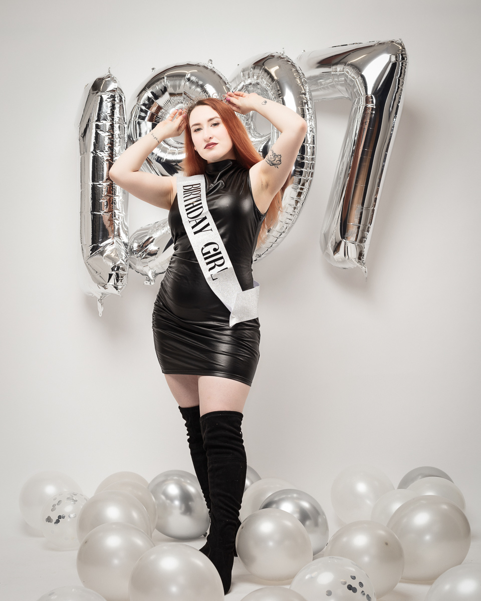 Birthday girl posing with balloons and tiara.