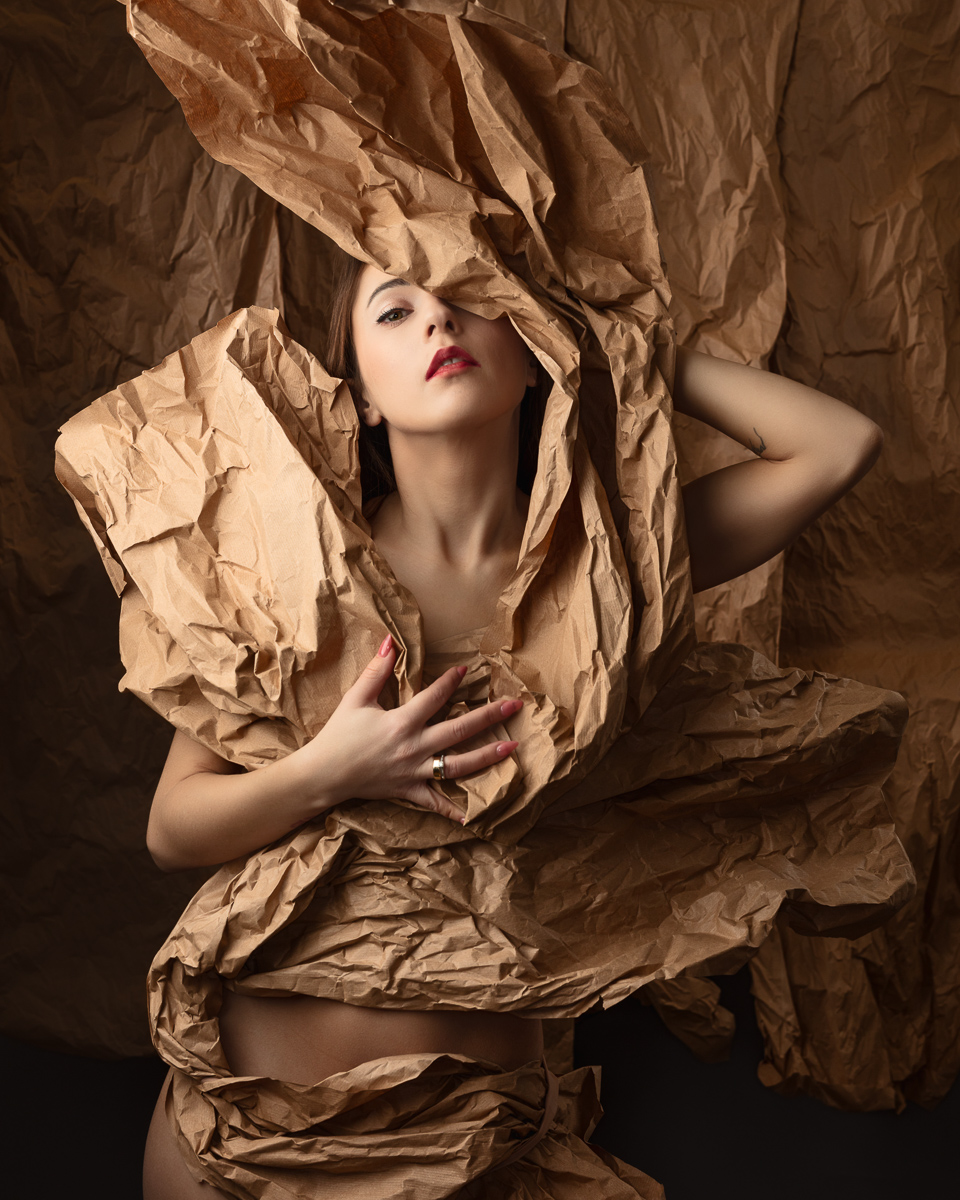 Woman wrapped in crumpled brown paper artfully posed.