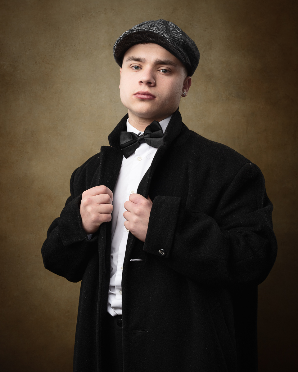 Man in overcoat and bowler hat posing confidently.