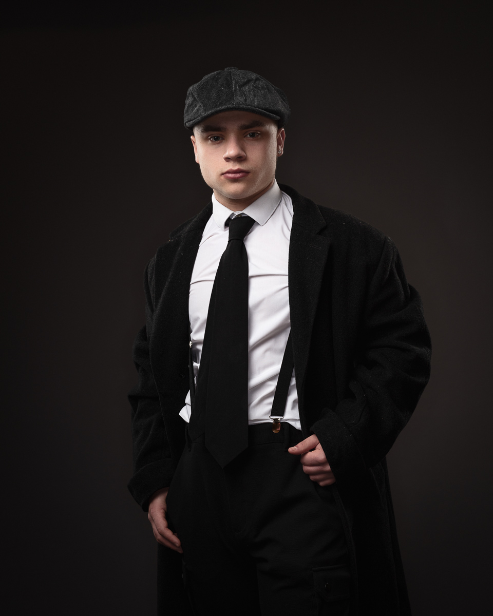 Man in vintage suit and flat cap posing confidently.