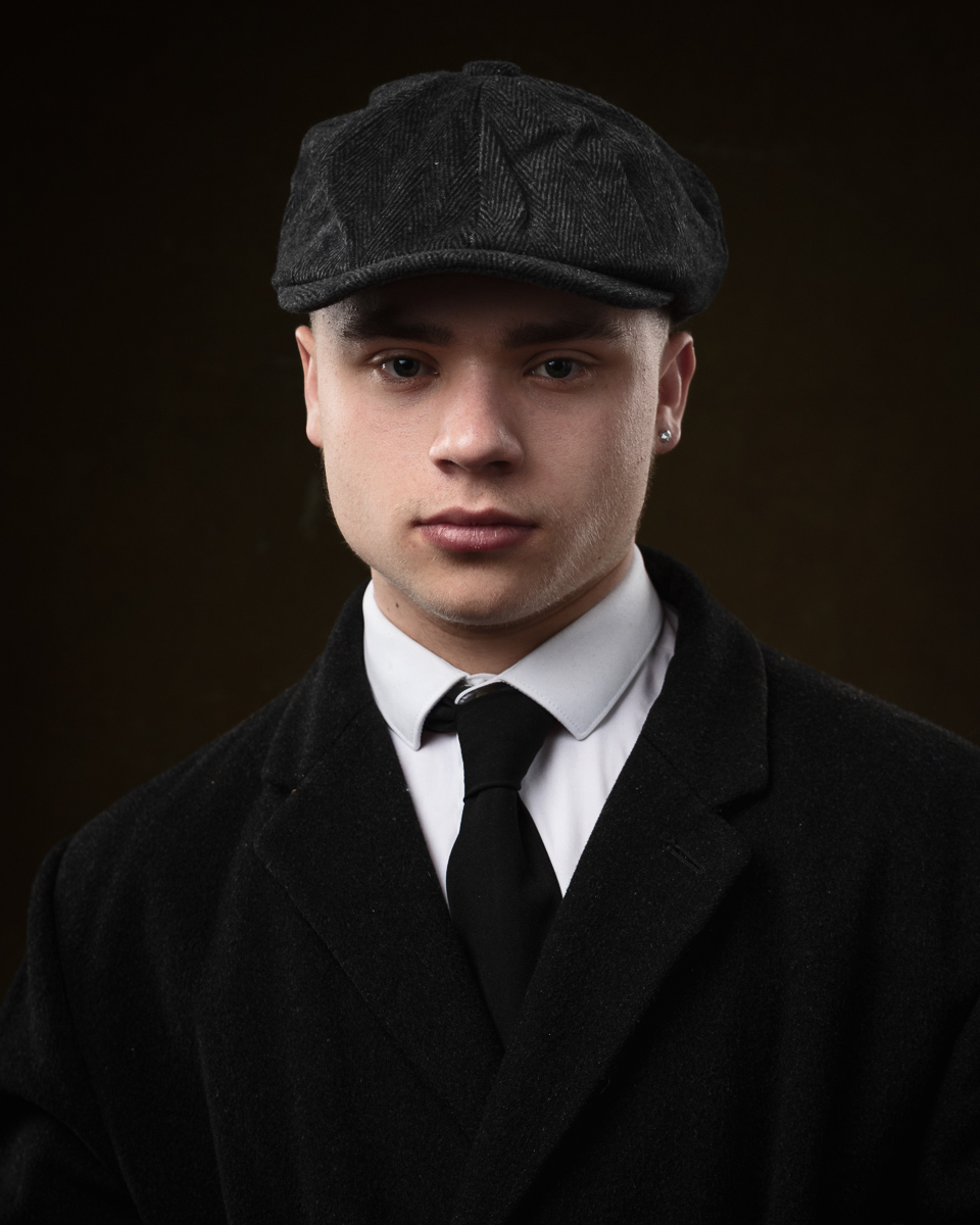 Person in flat cap and suit, serious expression.
