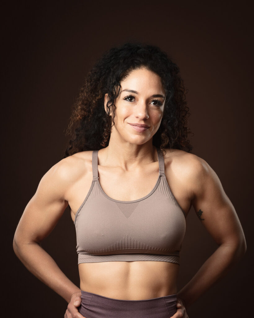 Fitness model wearing athletic gear on dark background.