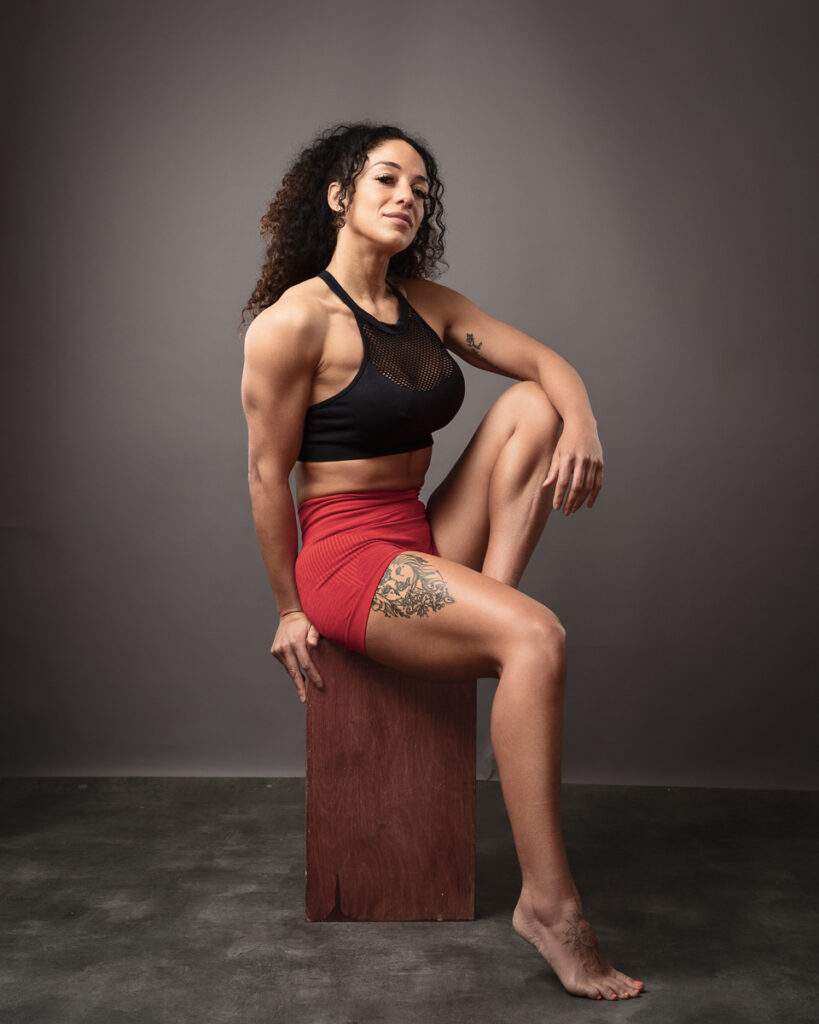 Woman in athletic wear poses confidently on wooden block.