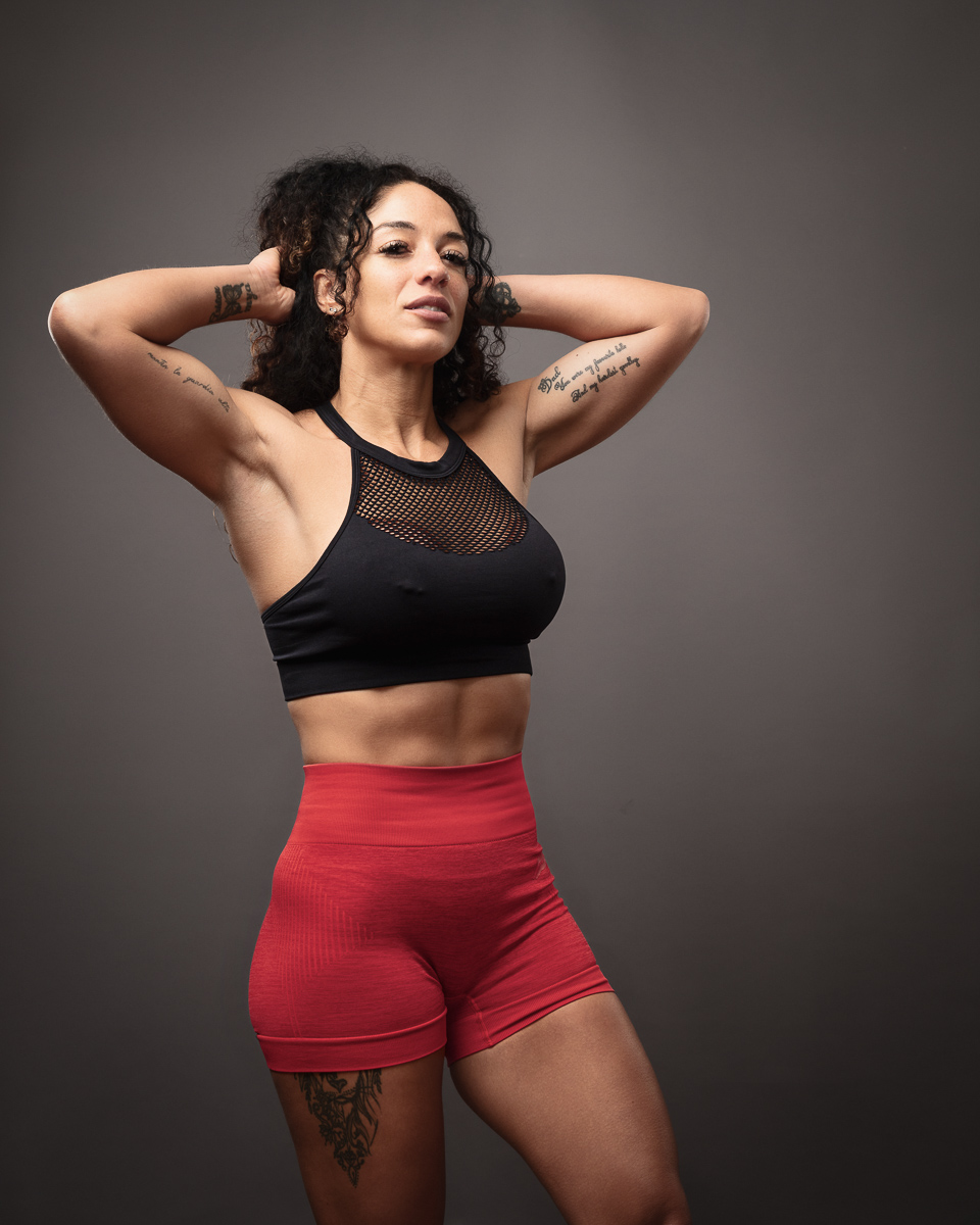Woman posing in athletic wear, tattoos visible.