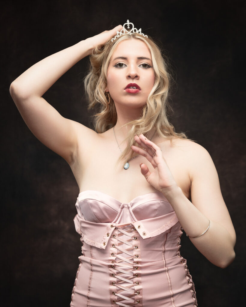 Woman in tiara and pink corset, elegant pose.
