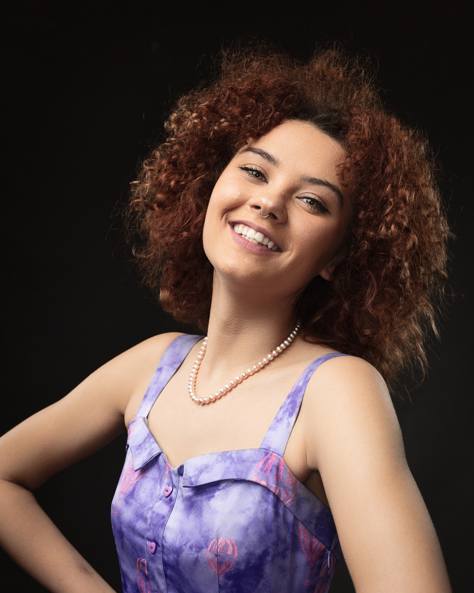 Smiling woman with curly hair and pearl necklace