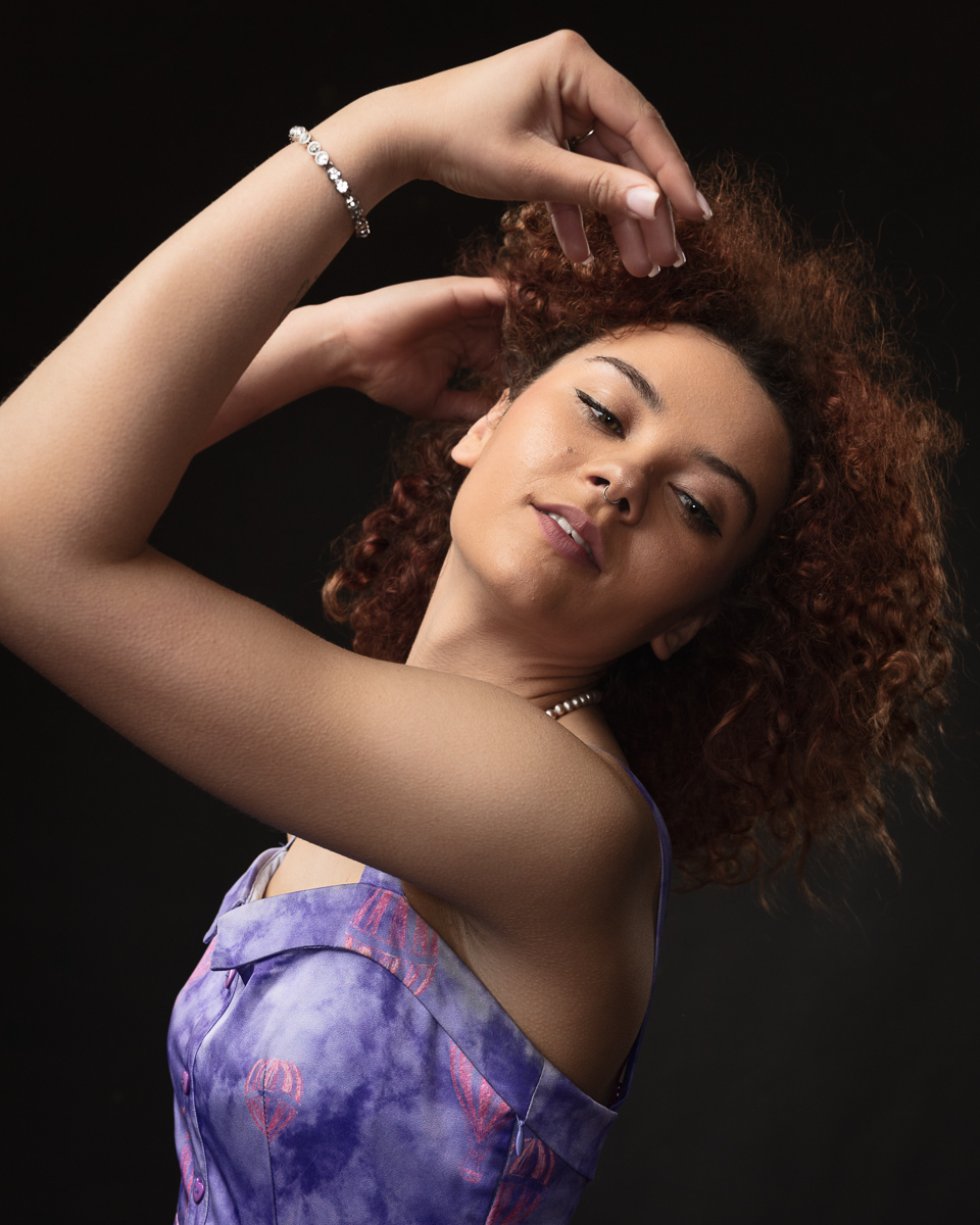 Person posing in purple dress, black background