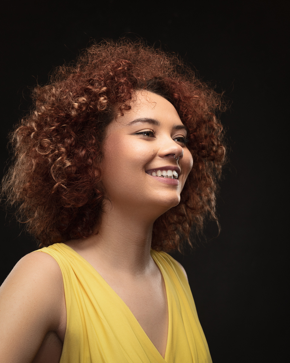 Woman smiling in yellow dress, curly hair