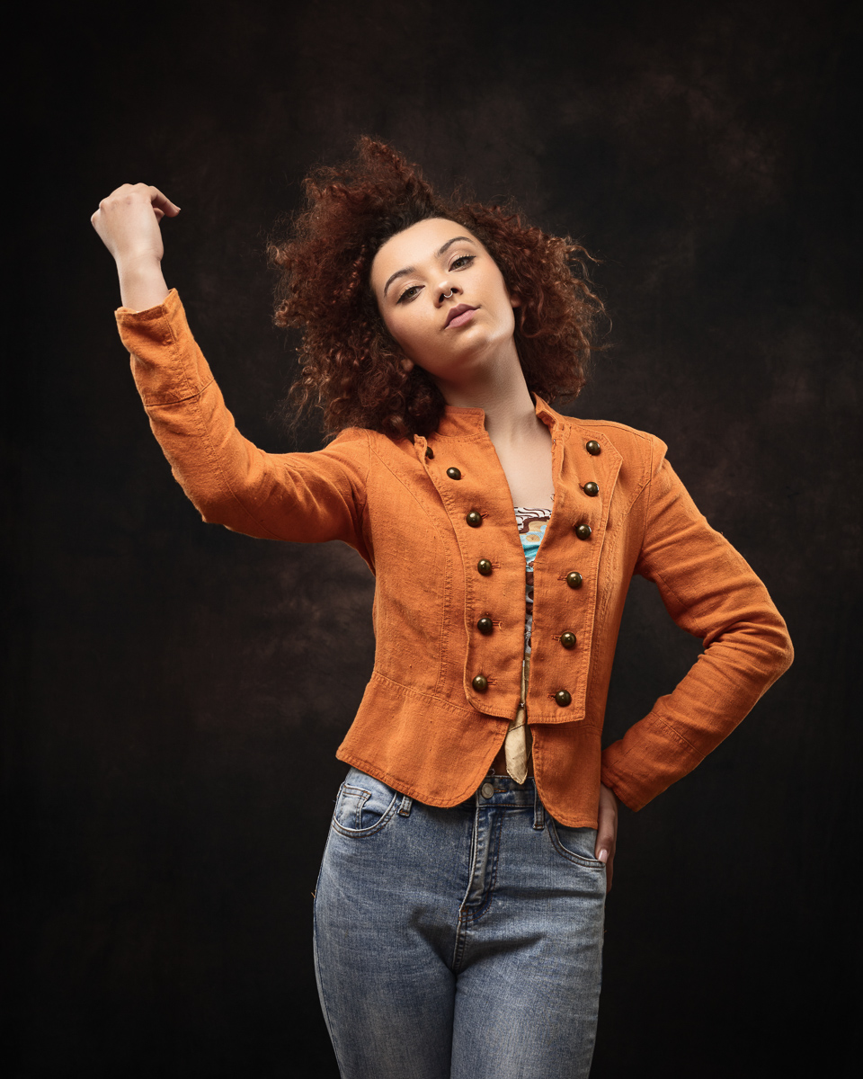 Fashionable woman in orange jacket and jeans.