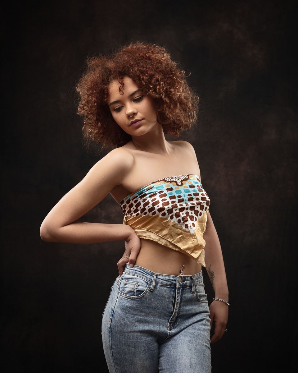 Woman posing in patterned top and jeans.