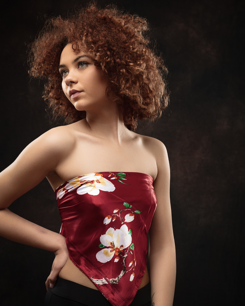 Woman wearing floral silk top, dark backdrop