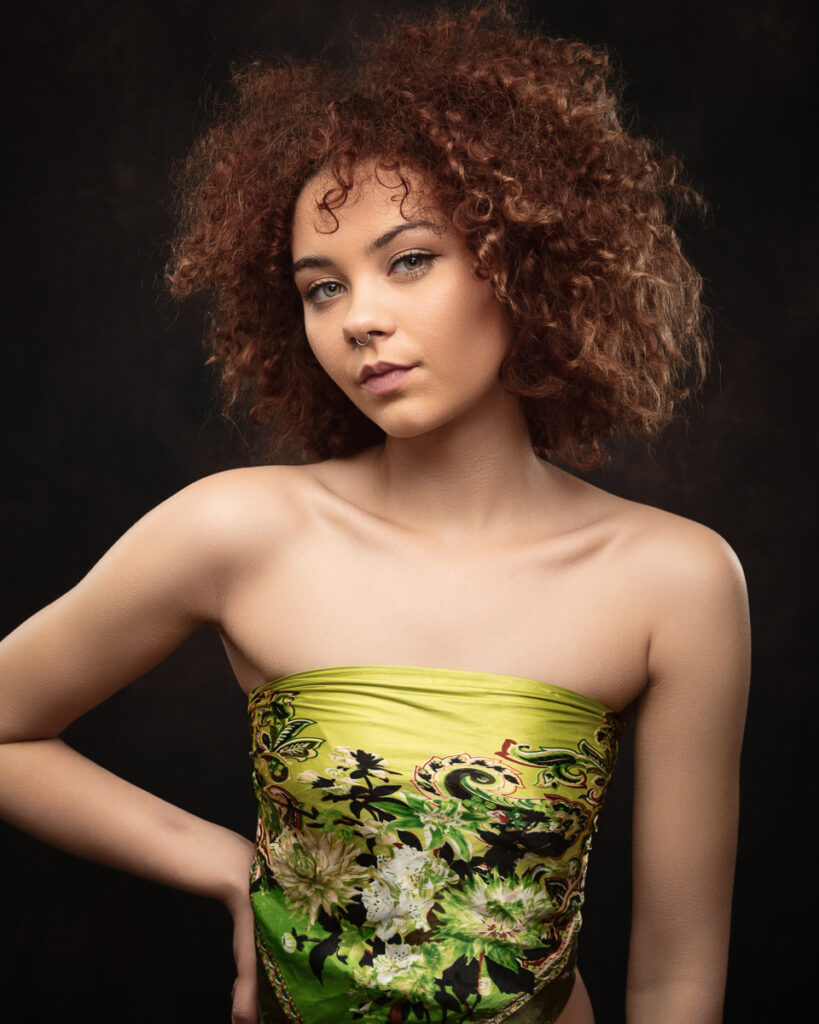 Person with curly hair, green patterned top
