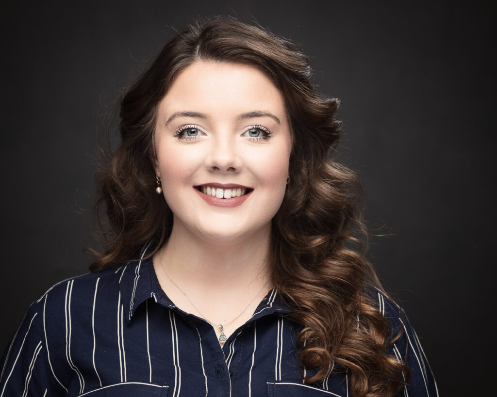 Smiling person with curly hair, striped shirt