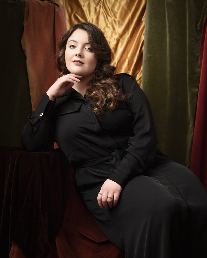 Person in black dress against velvet backdrop