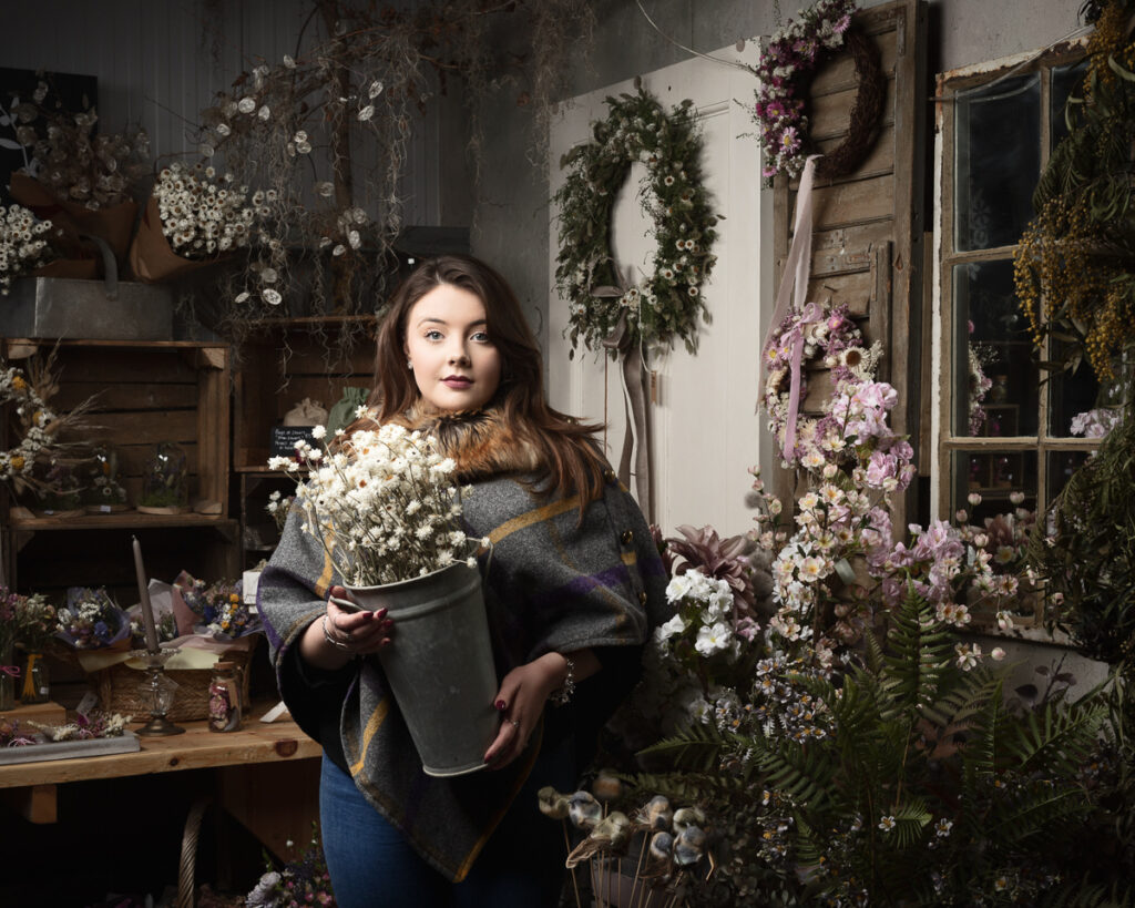 Woman holding flowers in rustic studio setting.