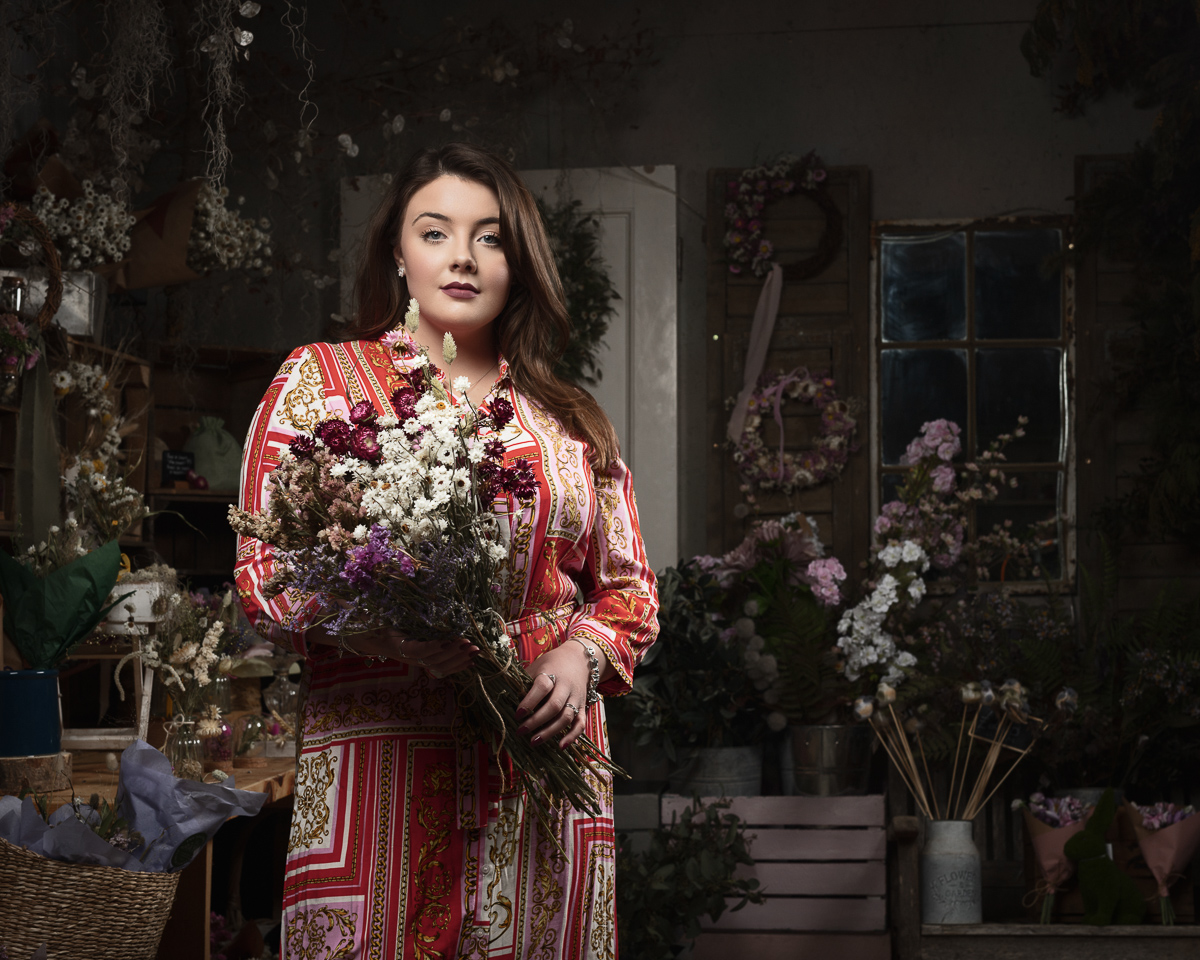 Woman in red dress holding dried flowers.