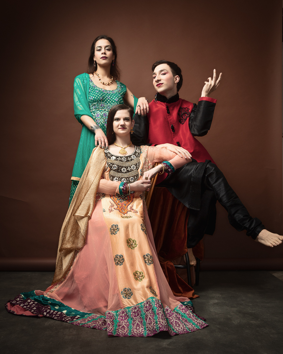 Three people in colourful traditional attire posing elegantly.