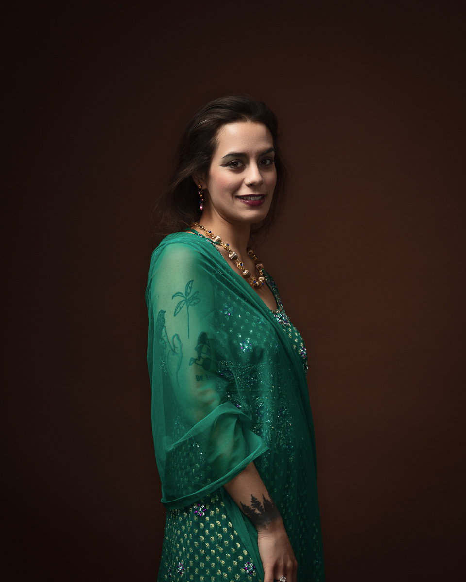 Woman in green saree smiling, brown background